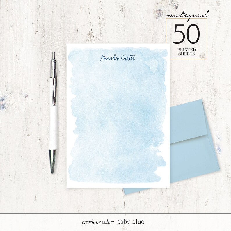 May include: A set of 50 personalised notepads with a light blue watercolour background. The notepad features the name "Amanda Carter" printed at the top. The envelope colour is baby blue.
