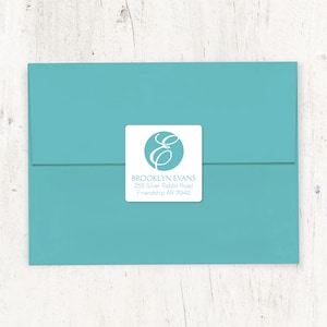 May include: A white square return address label with a blue circle containing a white cursive letter "E". The text "BROOKLYN EVANS" is printed below the circle, followed by the address "255 Silver Rabbit Road, Friendship AR 71942".