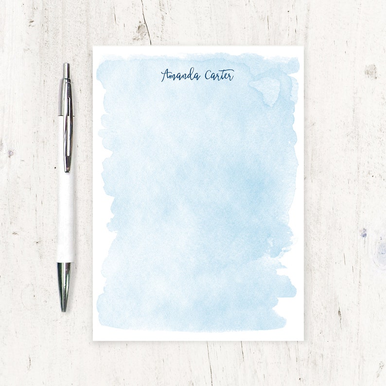 May include: A light blue watercolour notepad with the name "Amanda Carter" written in black ink at the top.