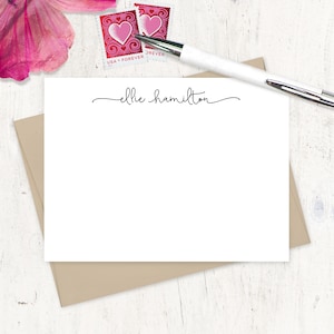 May include: A white card with a brown envelope behind it. The card has the text "ellie hamilton" written in cursive on it.