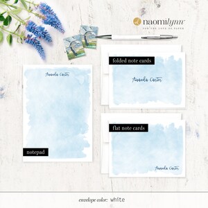 Puede incluir: Un juego de papeler&iacute;a con un dise&ntilde;o de acuarela azul claro con el nombre "Amanda Carter" impreso en cada pieza. El juego incluye un bloc de notas, tarjetas de notas plegadas y tarjetas de notas planas. El color del sobre es blanco.