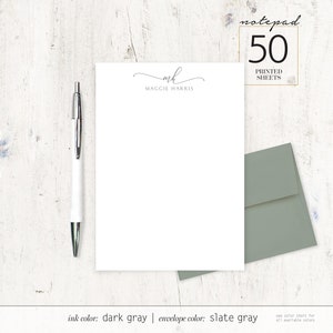 May include: A white notepad with 50 printed sheets. The notepad has a simple design with the initials "MH" and the name "Maggie Harris" printed at the top. The ink color is dark gray and the envelope color is slate gray.
