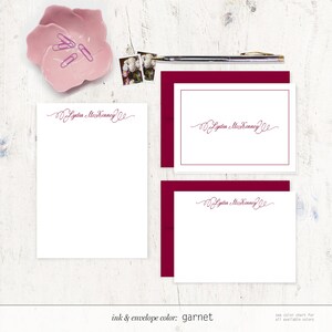 May include: A set of three white stationery cards with a burgundy envelope. The cards feature a handwritten script font with the name "Lydia McKinney" in a burgundy ink color. The text "ink & envelope color: garnet" is printed at the bottom of the image.