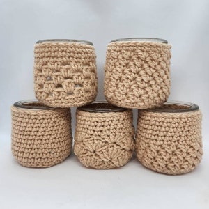 May include: Five crocheted beige candle jar covers with different stitch patterns.
