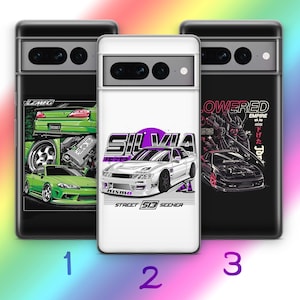 Puede incluir: Tres fundas para teléfono con diseños de coches. La primera es negra con gráficos de coches verdes y el texto "LZMFG". La segunda es blanca con un gráfico de coche blanco y el texto "SILVIA" y "STREET 513 SEEHER". La tercera es negra con un gráfico de coche y el texto "LOWERED EMPIRE".