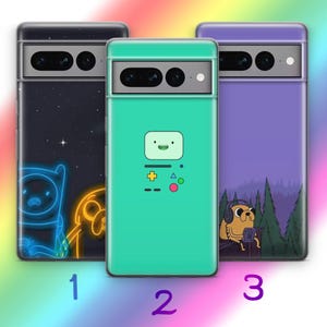 Puede incluir: Tres fundas para teléfono con diferentes diseños que presentan personajes de la serie animada Adventure Time. La primera funda tiene un fondo negro con un Finn y un Jake azul neón. La segunda funda tiene un fondo verde con una caricatura de un mando de videojuego. La tercera funda tiene un fondo morado con una caricatura de Jake con auriculares y sosteniendo un mando de videojuego.