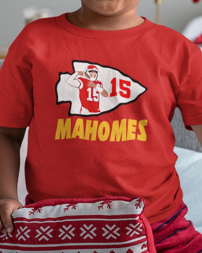 a young boy in a red shirt holding a pillow