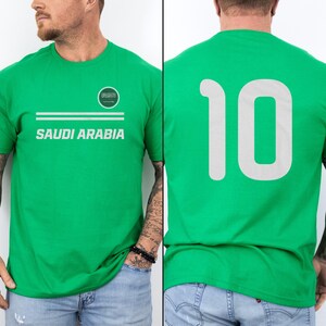 A man wearing a green t-shirt with the text "SAUDI ARABIA" printed on it.