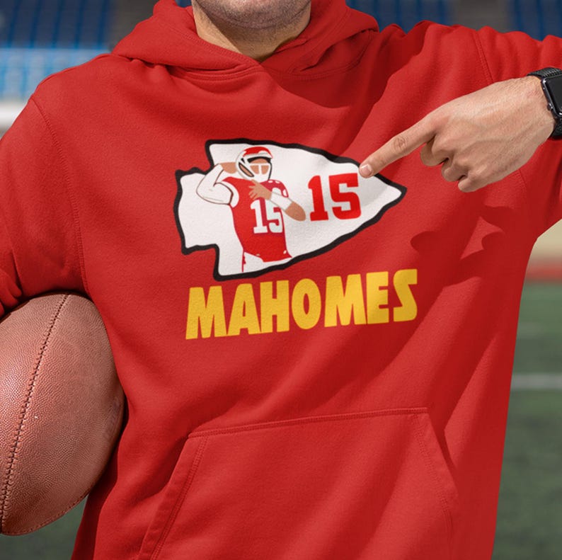 a man in a red hoodie pointing at a football