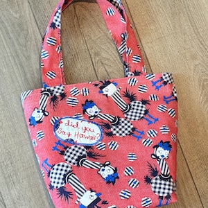 May include: Red tote bag with black and white checkered birds and the text "Did you say Hawaii?"