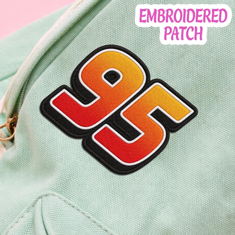 May include: An embroidered patch featuring the number 95 in a gradient of yellow, orange, and red with a thick black outline and white border. The patch is attached to a light mint green canvas fabric. The text EMBROIDERED PATCH is visible.