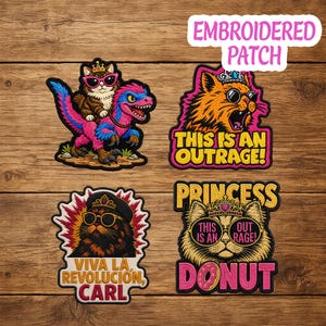 May include: Embroidered patches with cat designs. One patch shows a cat riding a dinosaur. Other patches feature cats with sunglasses and crowns, with text that reads "This is an Outrage!", "Viva la Revolución, Carl", and "Princess Donut".
