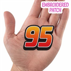 May include: An embroidered patch featuring the number 95 in a gradient of yellow, orange, and red. The digits have a white outline and a thick black border. The text EMBROIDERED PATCH is visible in the upper right corner of the image.