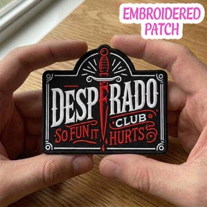 May include: Embroidered patch with the words "DESPERADO CLUB" in white and red lettering, with a dagger design. The phrase "SO FUN IT HURTS" is also included. The patch is black with a white border.