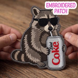 May include: An embroidered patch featuring a raccoon wearing black sunglasses and holding a silver Diet Coke can with a straw. The patch includes the text EMBROIDERED PATCH in pink letters at the top right corner of the image.