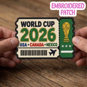 May include: Embroidered patch featuring a ticket design for the 2026 World Cup, with text reading "WORLD CUP 2026" and the USA, Canada, and Mexico flags. Includes a gold trophy and a small airplane icon.