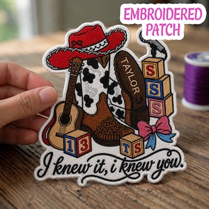 May include: An embroidered patch featuring a red cowboy hat, a brown and white cow-print cowboy boot, an acoustic guitar, a microphone, alphabet blocks with letters S, T, 1, 3, a pink and blue bow, and the text "TAYLOR" and "I knew it, i knew you."