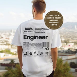 May include: White t-shirt with the word "Engineer" printed in black. The shirt also features the text "100% Biological" and a description of an engineer's traits. Available as a t-shirt, sweater, and hoodie.