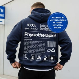May include: A navy blue hoodie featuring white text on the back that reads 100% BIOLOGICAL, Physiotherapist, and a detailed description. It includes a barcode, laundry symbols, and five icons labeled Observant, Patient, Supportive, Empathetic, Motivating.