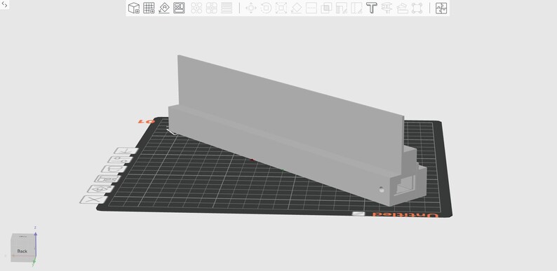May include: A light gray, rectangular 3D-printed object with a vertical panel and a rectangular base. The object is positioned on a black, grid-patterned surface. The design appears to be a component or part.