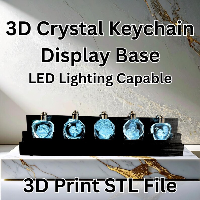 May include: A black display base holding five 3D crystal keychains. Each keychain has a silver cap and features a different image illuminated in blue. The text "3D Crystal Keychain Display Base LED Lighting Capable" is at the top.