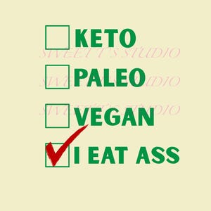 May include: A light beige graphic with green text and check boxes. The text reads "KETO", "PALEO", "VEGAN", and "I EAT ASS". The "I EAT ASS" box is checked with a red tick.