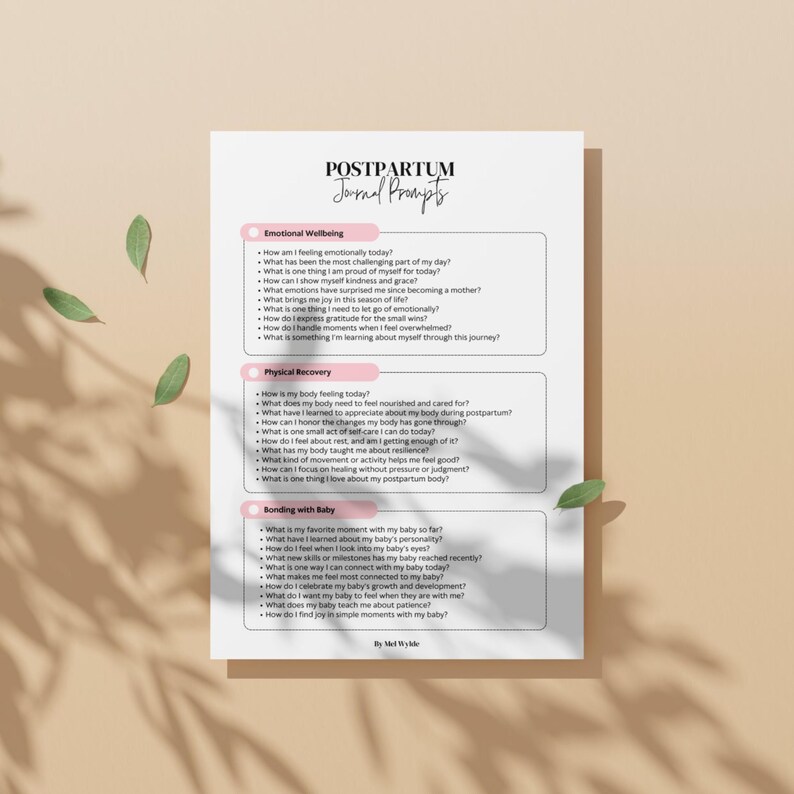 May include: A white journal page with the title "POSTPARTUM Journal Prompts" and sections on emotional wellbeing, physical recovery, and bonding with baby. The journal prompts are printed in black text on a beige background.