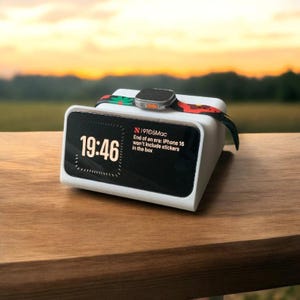 Può includere: Un supporto di ricarica bianco con uno schermo nero che mostra l'ora 19:46 e il testo "19105Mac Fine di un'era: iPhone 16 non includerà adesivi nella confezione". Uno smartwatch con un cinturino nero è posizionato sopra il supporto.