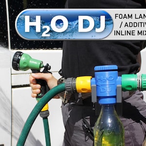 May include: A person is holding a green and black water nozzle, spraying water. The image shows a blue and yellow inline mixer with the text "H2O DJ" and "FOAM LANCE / ADDITIVE INLINE MIXER". The mixer is connected to a green hose and a clear bottle.