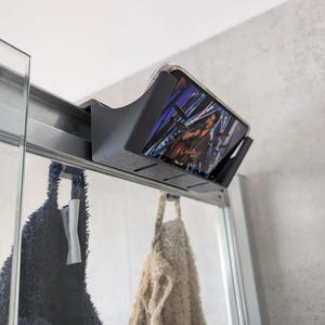 Soporte para teléfono móvil para la ducha con toallero integrado.