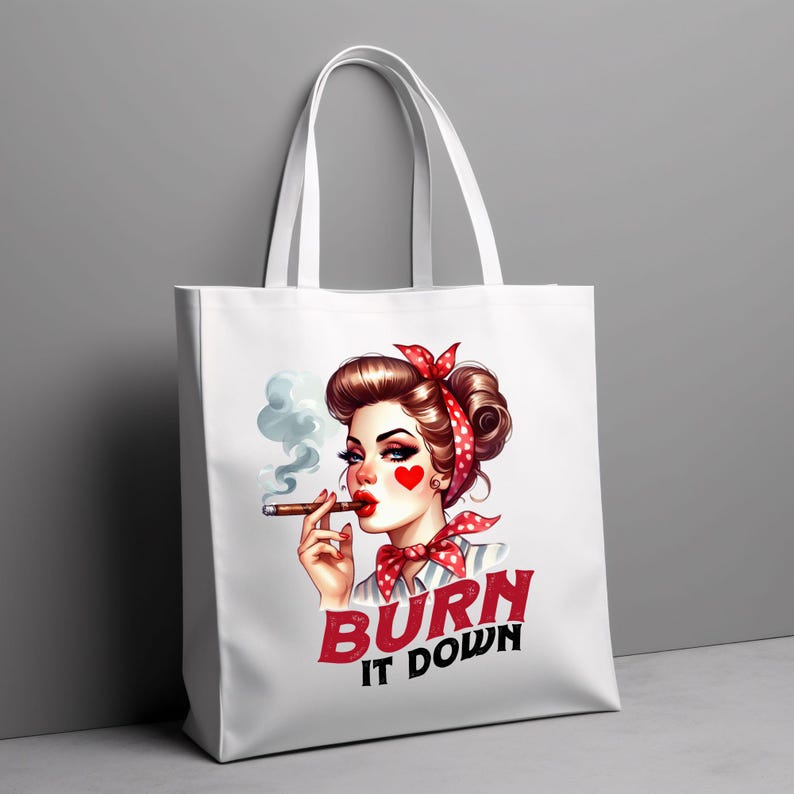 Puede incluir: Bolso tote blanco con una ilustraci&oacute;n retro de una mujer con un pa&ntilde;uelo de lunares rojos y una mejilla en forma de coraz&oacute;n. Est&aacute; fumando un cigarro. El texto "BURN IT DOWN" est&aacute; impreso en rojo y negro.