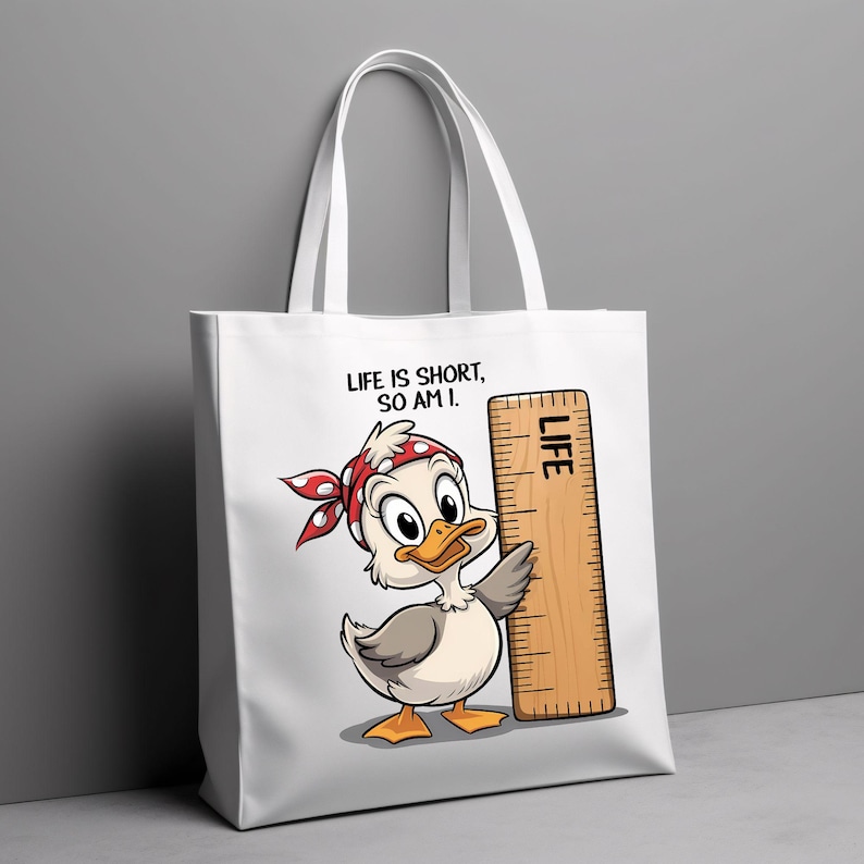 May include: White canvas tote bag featuring a cartoon duck wearing a red and white bandana. The duck is holding a wooden ruler labelled "LIFE". The text on the bag reads "LIFE IS SHORT, SO AM I."