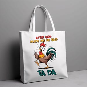 May include: White tote bag featuring a cartoon rooster illustration and the text "After God Made Me He Said Ta Da".