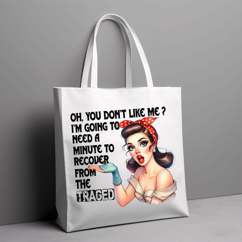 Puede incluir: Bolso tote blanco con una ilustraci&oacute;n retro de una mujer con una diadema roja de lunares y guantes azules. El texto en el bolso dice: "OH, YOU DON'T LIKE ME? I'M GOING TO NEED A MINUTE TO RECOVER FROM THE TRAGED."