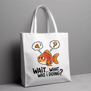 May include: White tote bag featuring a cartoon goldfish with thought bubbles above its head. One thought bubble contains a pizza slice, while the other has a question mark. The text on the bag reads "WAIT... WHAT WAS I DOING?"