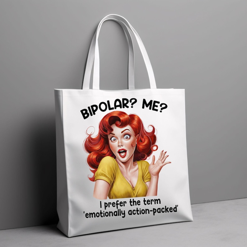 Puede incluir: Bolso tote blanco con una ilustraci&oacute;n retro de una mujer pelirroja con expresi&oacute;n de sorpresa. El texto dice "&iquest;BIPOLAR? &iquest;YO?" y "Prefiero el t&eacute;rmino 'emocionalmente lleno de acci&oacute;n'". El bolso tiene asas blancas.