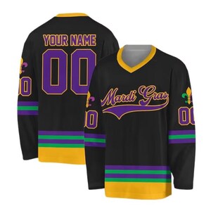 May include: Black hockey jersey with gold, purple, and green accents. The front features "Mardi Gras" in purple script. The back has "YOUR NAME" above a purple "00". The sleeves have a purple and green stripe.