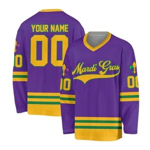 May include: Purple hockey jersey with gold and green accents. The jersey features the text "YOUR NAME" and the number "00" on the back. The front displays "Mardi Gras" in gold script. The sleeves have gold and green stripes.