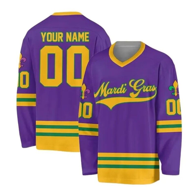May include: Purple hockey jersey with gold and green accents. The jersey features the text "YOUR NAME" and the number "00" on the back. The front displays "Mardi Gras" in gold script. The sleeves have gold and green stripes.