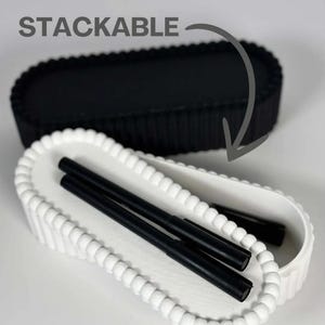 May include: Stackable black and white oval trays. The white tray has a beaded edge and contains black pens. The black tray is on top. The word "STACKABLE" is in the image.