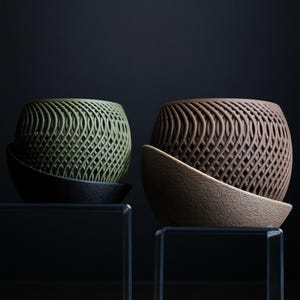 May include: Two decorative planters. One is olive green, the other is brown. Both have a woven design and sit in matching, curved saucers. The planters are on a clear surface against a dark background. These planters are ideal for home decor.