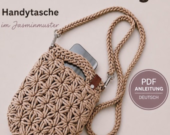 Puede incluir: Una funda de ganchillo beige para teléfono con un patrón de punto de jazmín, una correa larga trenzada con clips metálicos y una pequeña lengüeta de cuero marrón. El texto dice Häkelanleitung, Handytasche im Jasminmuster y PDF ANLEITUNG DEUTSCH.
