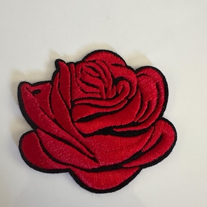May include: A red rose patch with black embroidered outlines. The patch features a detailed design of a blooming rose, with multiple petals and a black border. The patch is likely for clothing or accessories.