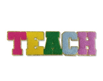 Op de afbeelding: Een kleurrijke patch met het woord "TEACH". Elke letter heeft een andere kleur: roze, geel, groen, lichtblauw en paars. De letters hebben een fuzzy textuur en zijn omrand met gouden glitter.
