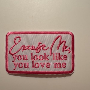 May include: Embroidered patch with the text "Excuse Me you look like you love me" in pink script on a white background. The patch has a pink border and a rectangular shape.