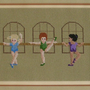 Könnte beinhalten: Sechs Mädchen in bunten Trikots führen eine Ballet-Pose an einer Barre aus. Die Mädchen stehen in einer Reihe, jedes in einem Trikot in einer anderen Farbe. Die Barre ist braun und hat einen weißen Hintergrund.