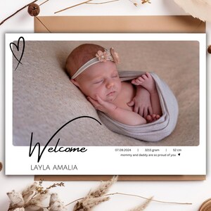 Op de afbeelding: Een witte kaart met een foto van een slapende pasgeboren baby. De kaart zegt "Welkom Layla Amalia" en bevat de geboortedatum van de baby, het gewicht (3215 gram) en de lengte (52 cm). De kaart heeft een eenvoudig hartontwerp.