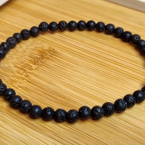 Könnte beinhalten: Ein schwarzes Armband aus Lavasteinen.