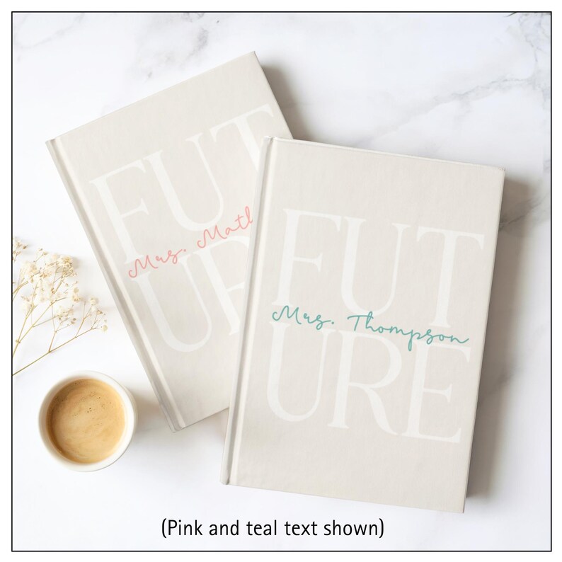 A flat lay image of two journals laying one on top of the other.  The design is the same except that the bottom journal has pink writing that says "Mrs. Mathews" and the top journal has teal text with the personalization "Mrs. Thompson".  The journals are laid so that you can see both, while still being stacked.  A small cup of coffee is shown.  All items are set on a white marble background.  Text says: (Pink and teal text shown.)