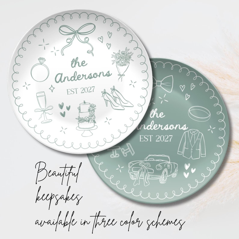 May include: Two round ceramic plates featuring sage green line art illustrations. One plate is white with green designs, the other is green with white designs. Both feature the text "the Andersons EST 2027" surrounded by wedding icons like a ring, cake, and car.